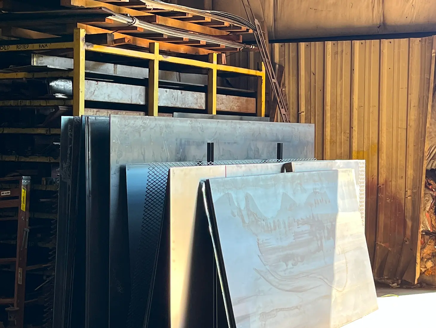 Warehouse filled with lots of different types of metal, including steel sheets, metal rods, and other objects